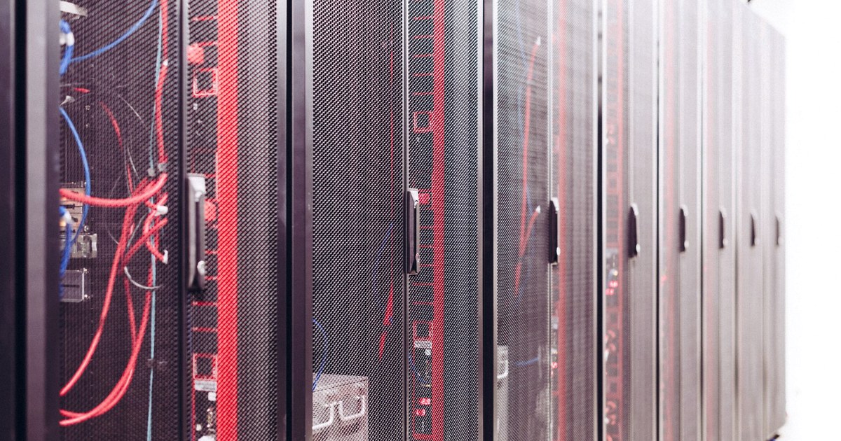 Rows of black server racks with red and blue cabling in a data center