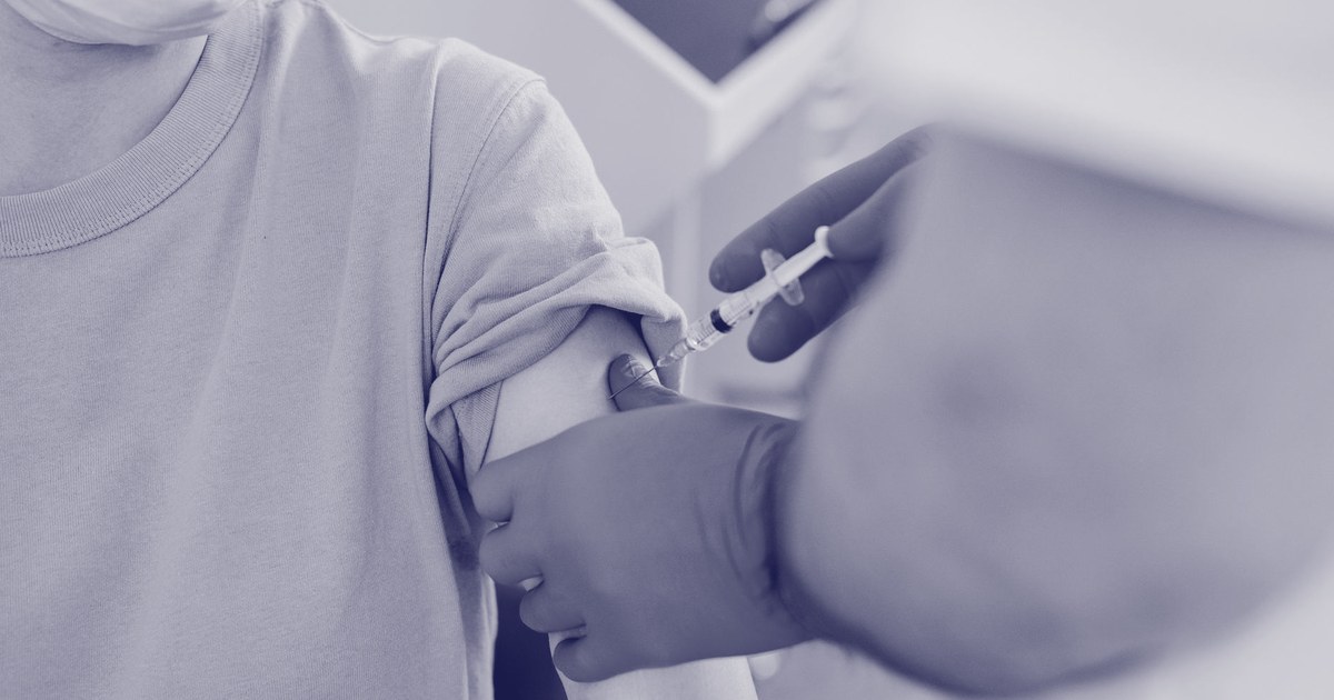 Close-up of a gloved health worker administering a vaccine injection into a patient's upper arm