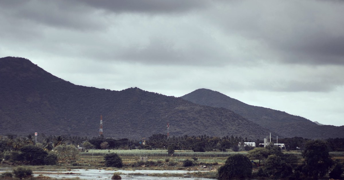 Monsoon storm clouds over rain-fed farmland and flooded fields in the Cauvery basin, Karnataka, with hills in the background