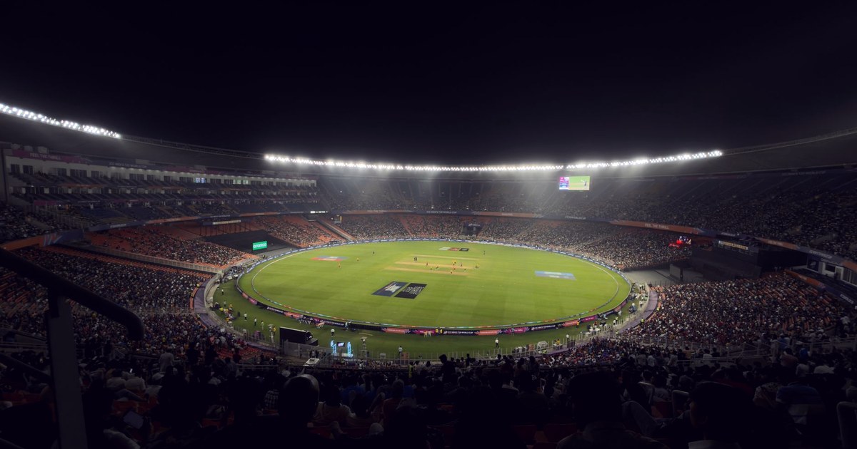 A packed night crowd inside a floodlit Indian cricket stadium watching an international match