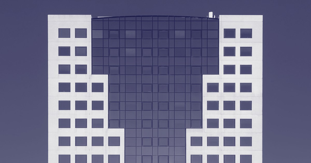 A modern corporate office tower with a geometric glass and concrete facade against a clear sky