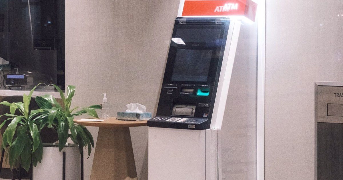 A lone self-service ATM standing in a quiet, empty bank lobby with no teller in sight
