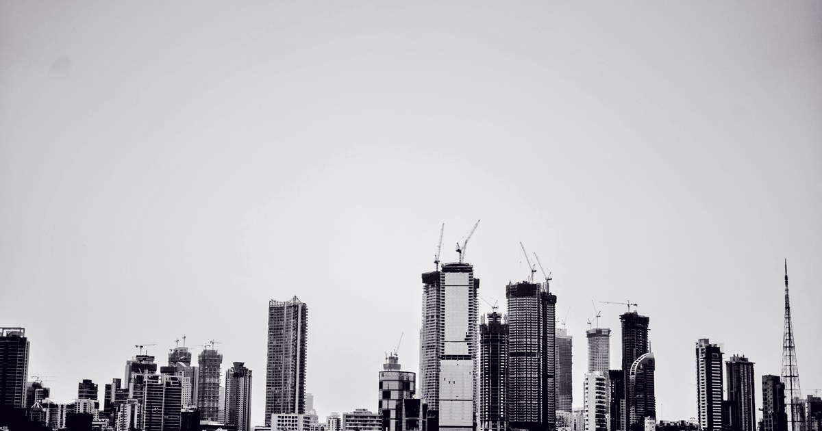 A grayscale view of Mumbai's financial-district skyline, with high-rise towers under construction and cranes against an overcast sky