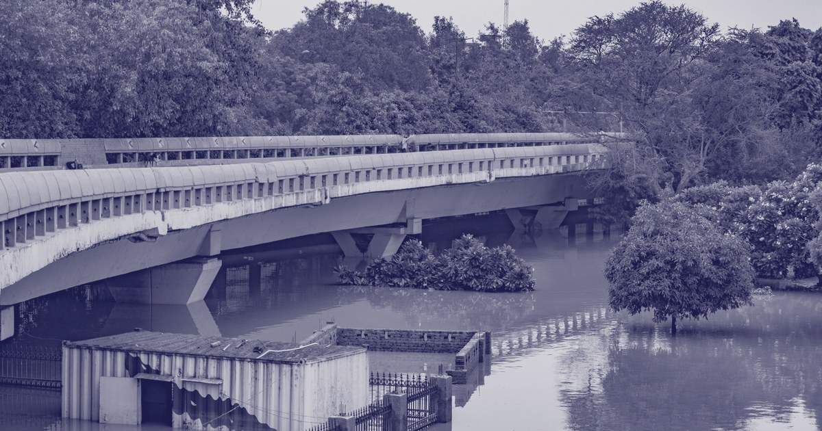 A pedestrian bridge over floodwater with a partly submerged brick structure in New Delhi during the monsoon