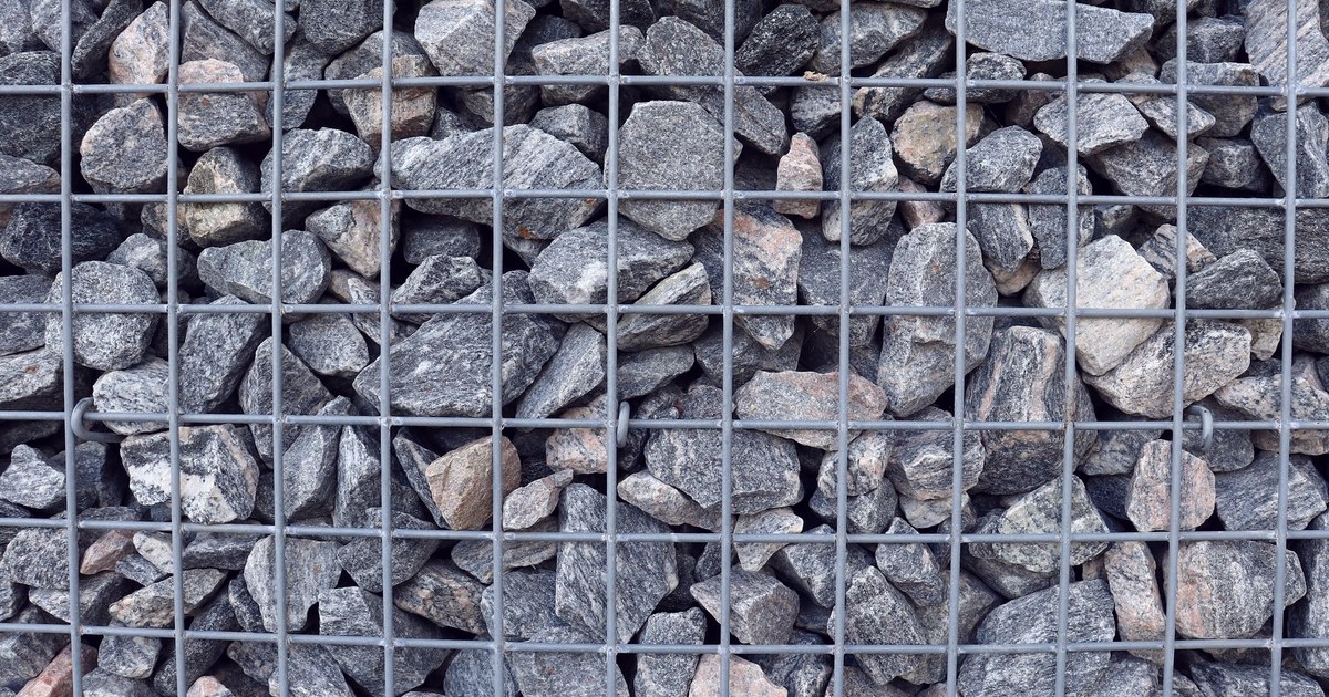 Close-up of a wire-mesh gabion cage packed tightly with crushed stone, the same wire-and-fill barrier design as the Hesco bastions at the centre of the Army tenders