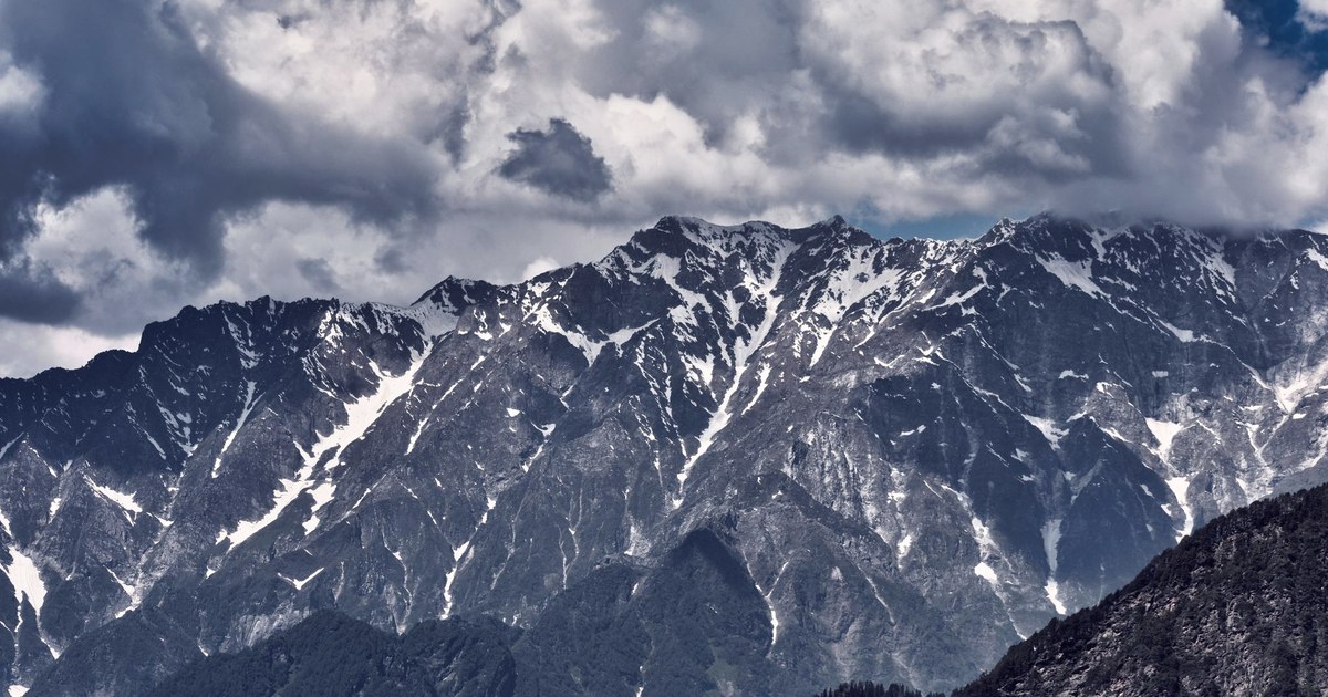 Snow-covered Himalayan peaks under a dramatic cloudy sky in Uttarkashi, Uttarakhand, India