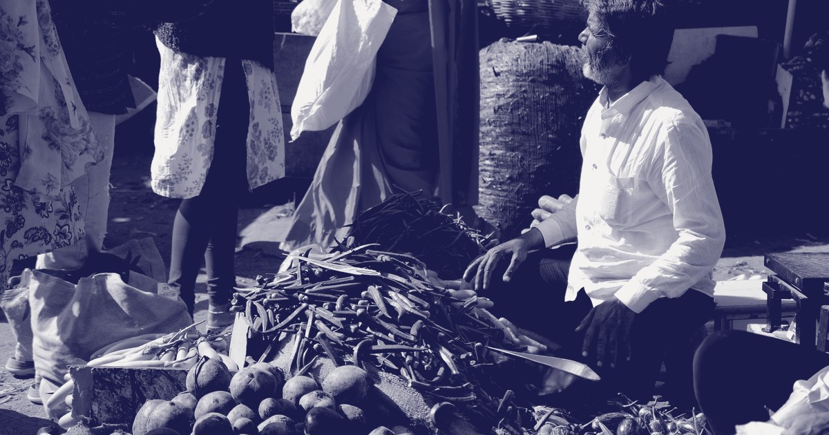 A vendor sits behind piles of fresh vegetables at an Indian market stall, part of the basket the new CPI series reweighted