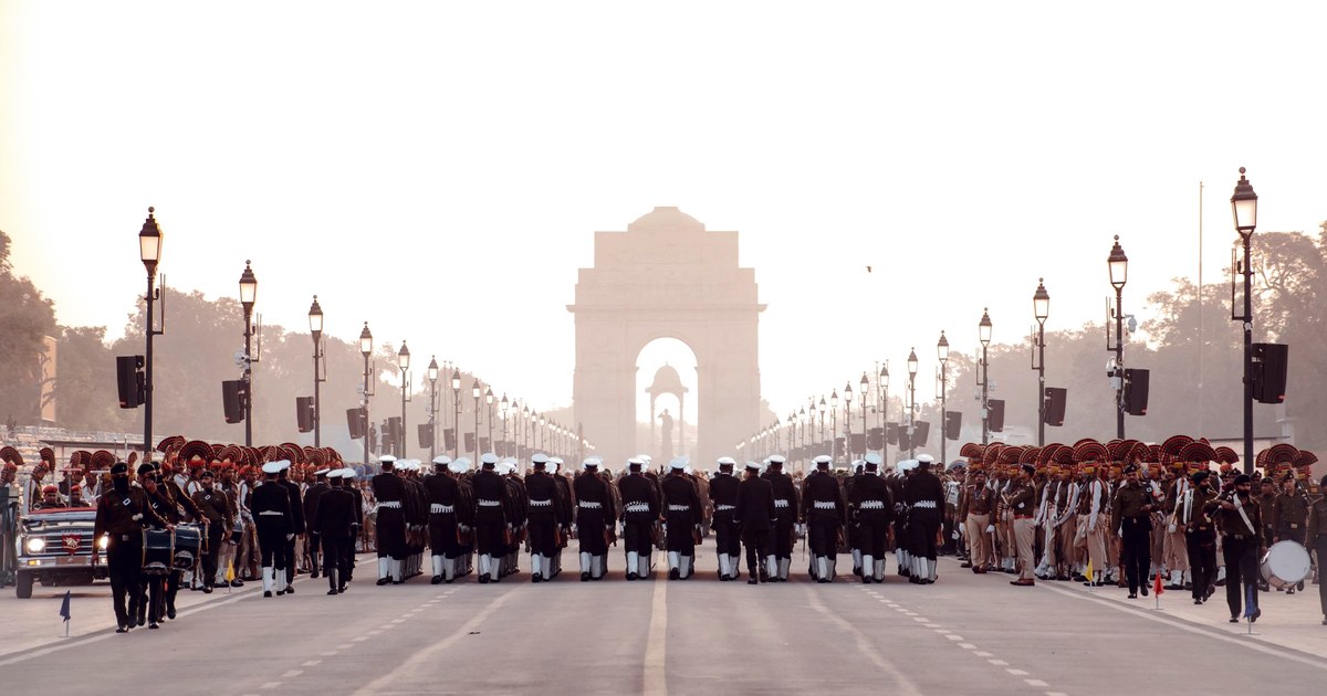 Indian tri-service military personnel marching in a parade rehearsal toward India Gate in New Delhi at dawn