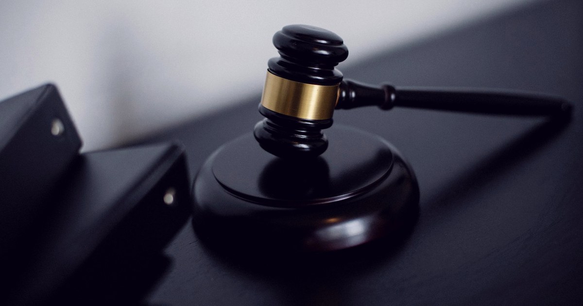 A wooden gavel resting on its sound block on a dark courtroom desk