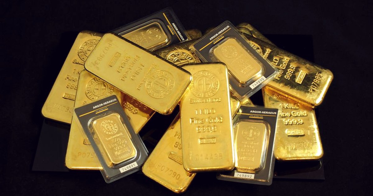 A pile of stacked gold bullion bars on a dark background