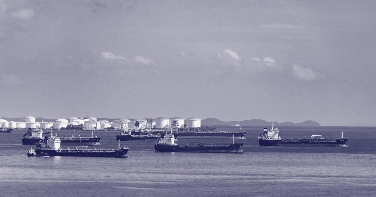 Oil and gas tankers anchored near a coastal storage terminal, with more ships waiting offshore under a clear sky