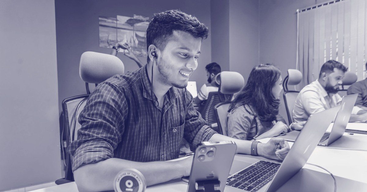 Young professionals at an Indian technology office working on laptops and a phone, part of the country's GCC and IT-services workforce