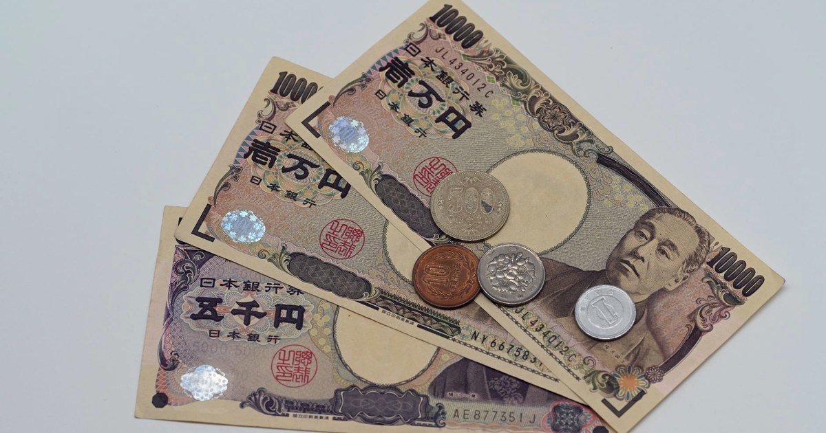 A fanned arrangement of Japanese yen banknotes and coins on a flat surface.