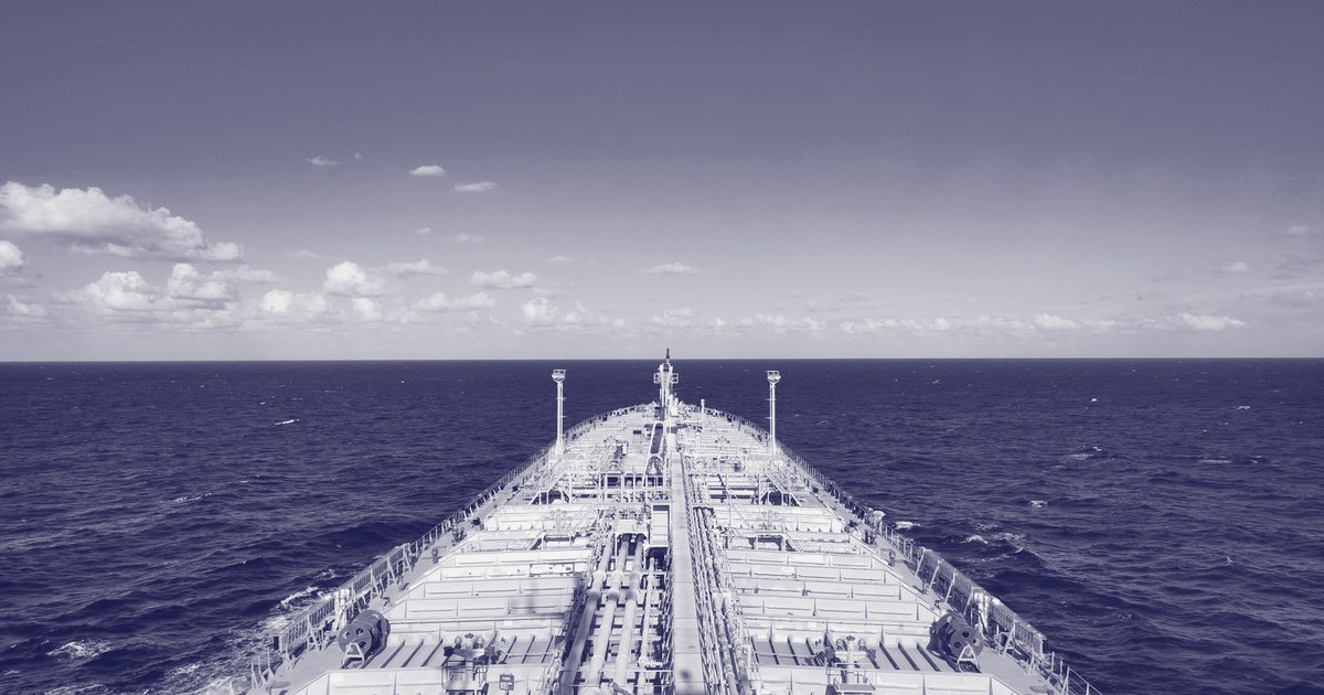 The bow of a large oil tanker cutting through open blue ocean under a clear sky