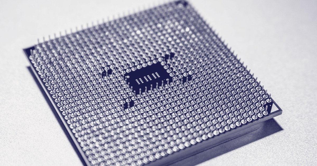 Macro shot of a computer processor's underside, showing rows of gold connector pins against a pale surface