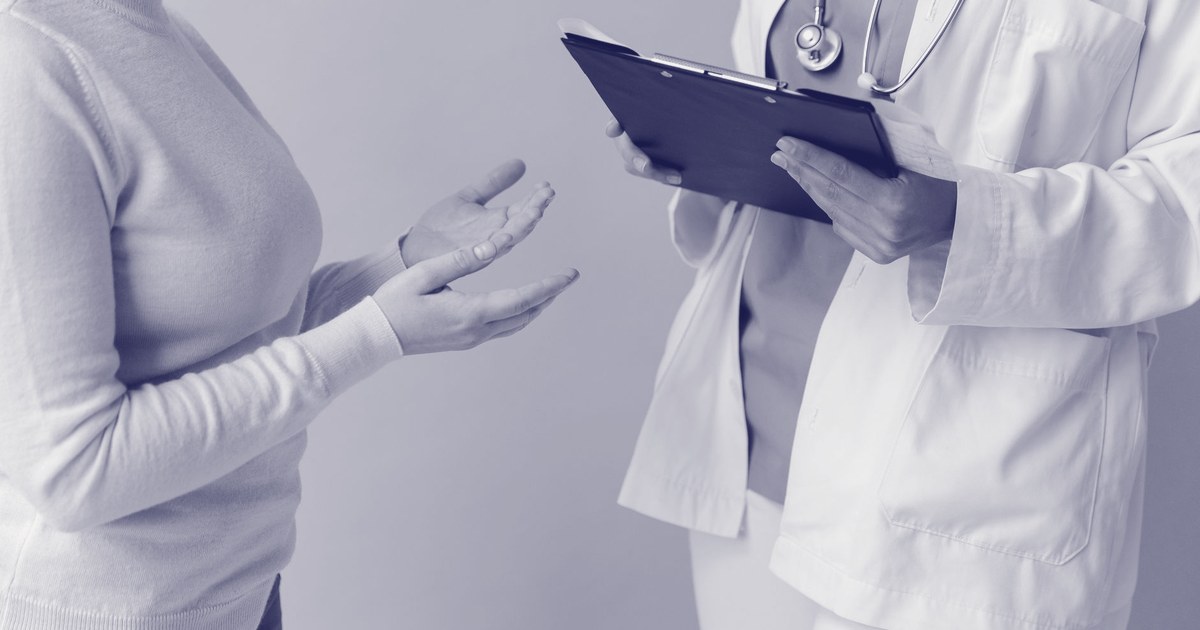A doctor in a white coat holding a clipboard speaks with a patient, shown from the shoulders down in a tinted duotone
