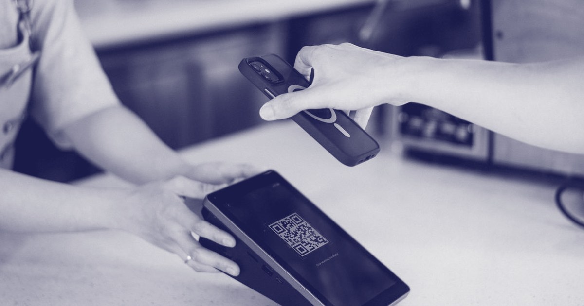 Close-up of a customer scanning a QR code on a payment terminal with a smartphone to complete a digital payment