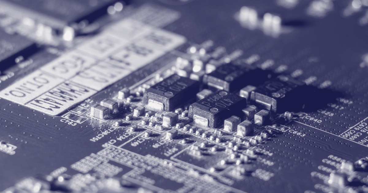 Close-up of a blue circuit board with black capacitors and small surface-mounted components