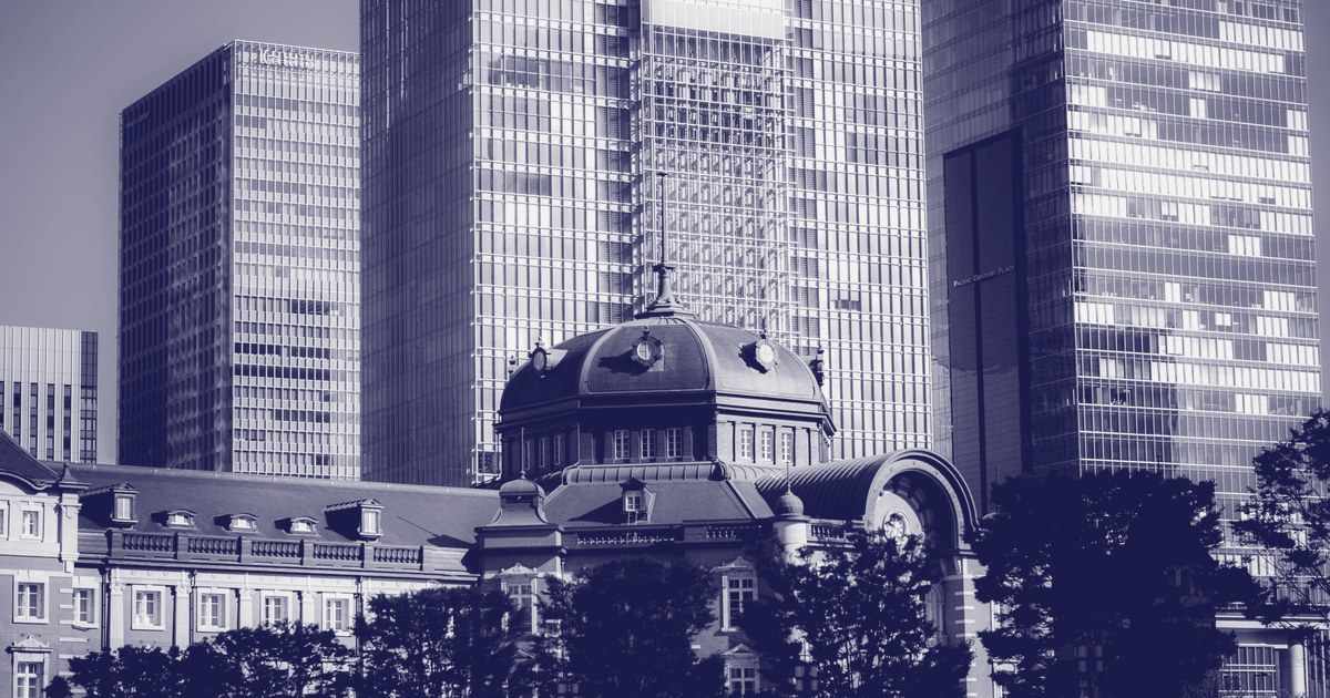 Tokyo Station's historic red-brick building framed by glass skyscrapers in the Marunouchi financial district