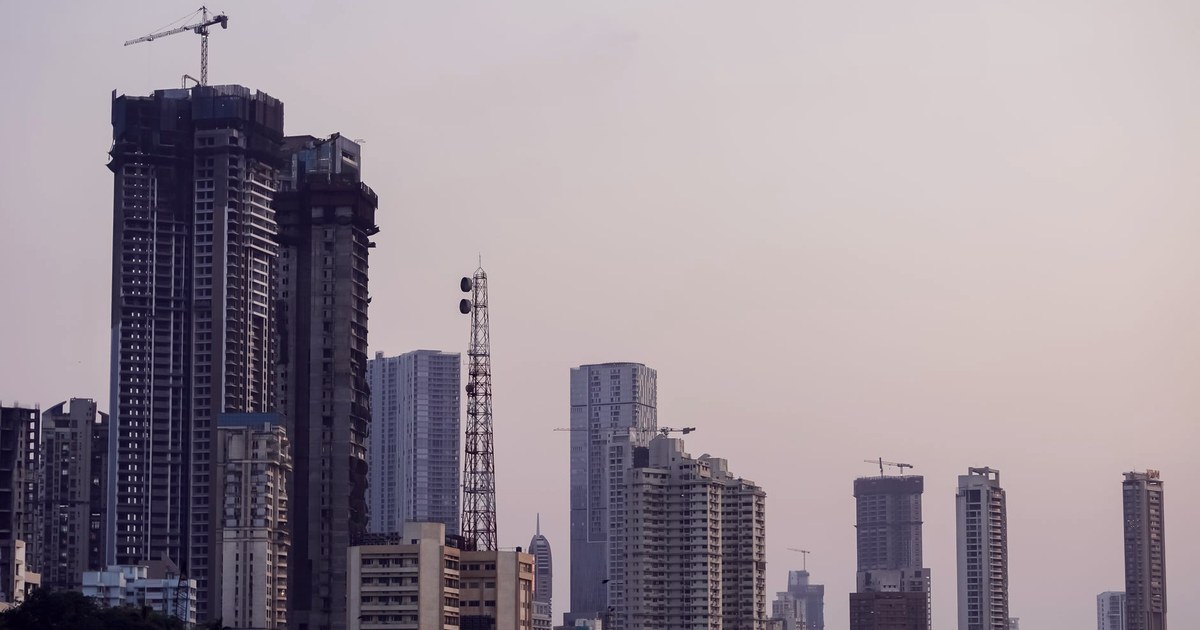 Mumbai's high-rise skyline at dusk, with a construction crane atop an unfinished tower