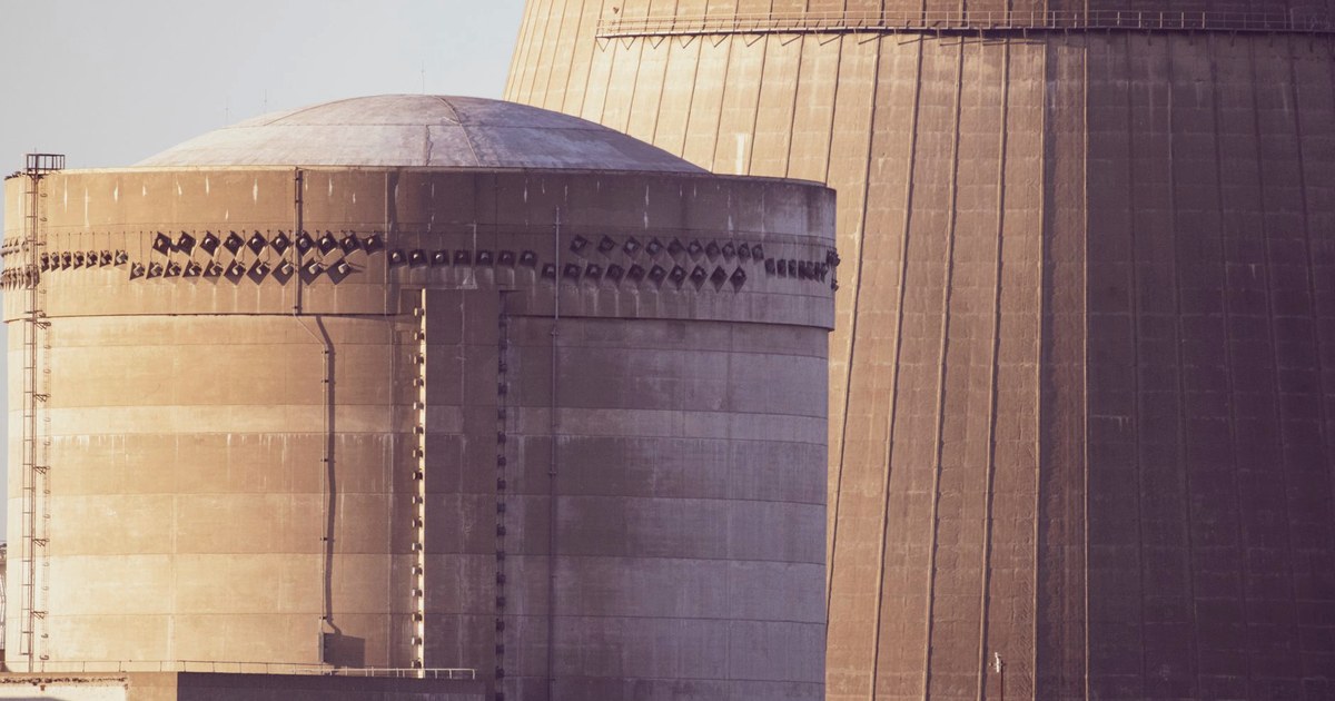Close-up view of a nuclear reactor containment dome beside a cooling tower in golden late-afternoon light