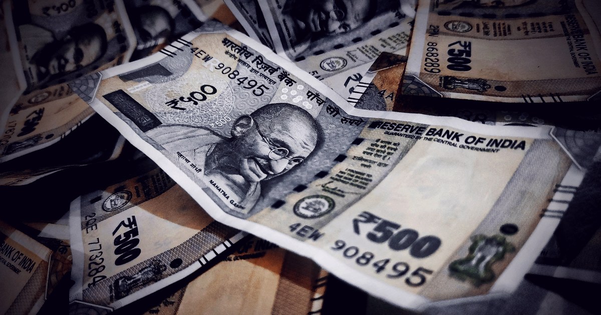 A close-up pile of Indian 500-rupee banknotes, the 'Reserve Bank of India' text and Mahatma Gandhi portrait clearly visible