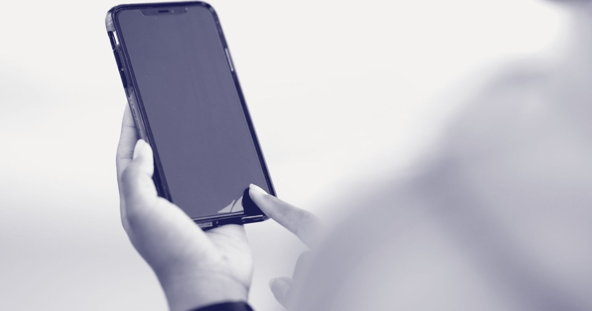 A close-up of a hand holding a smartphone with its screen turned off