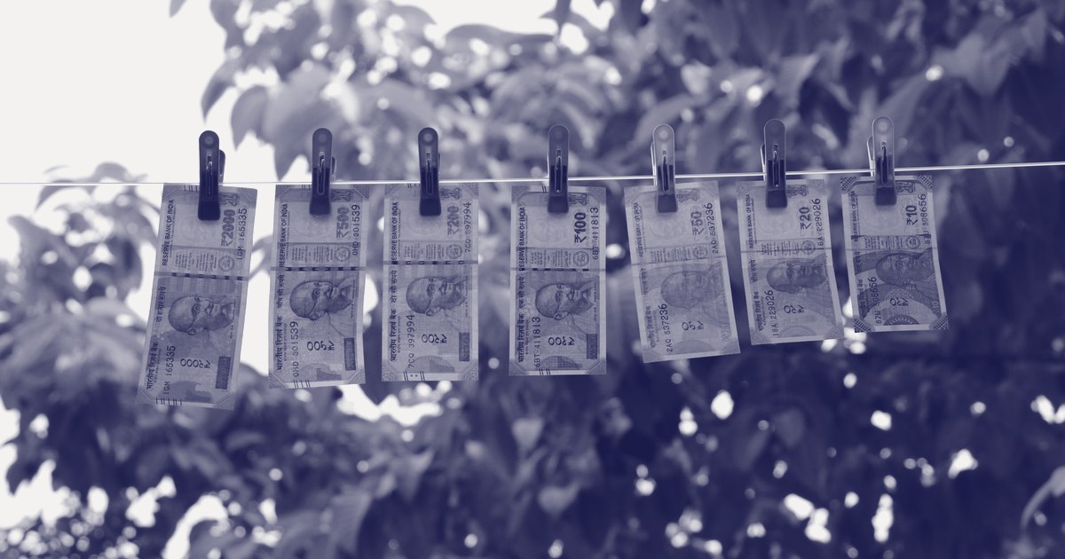 Indian rupee banknotes of every denomination, including the pink Rs 2,000 note, pegged to a clothesline outdoors