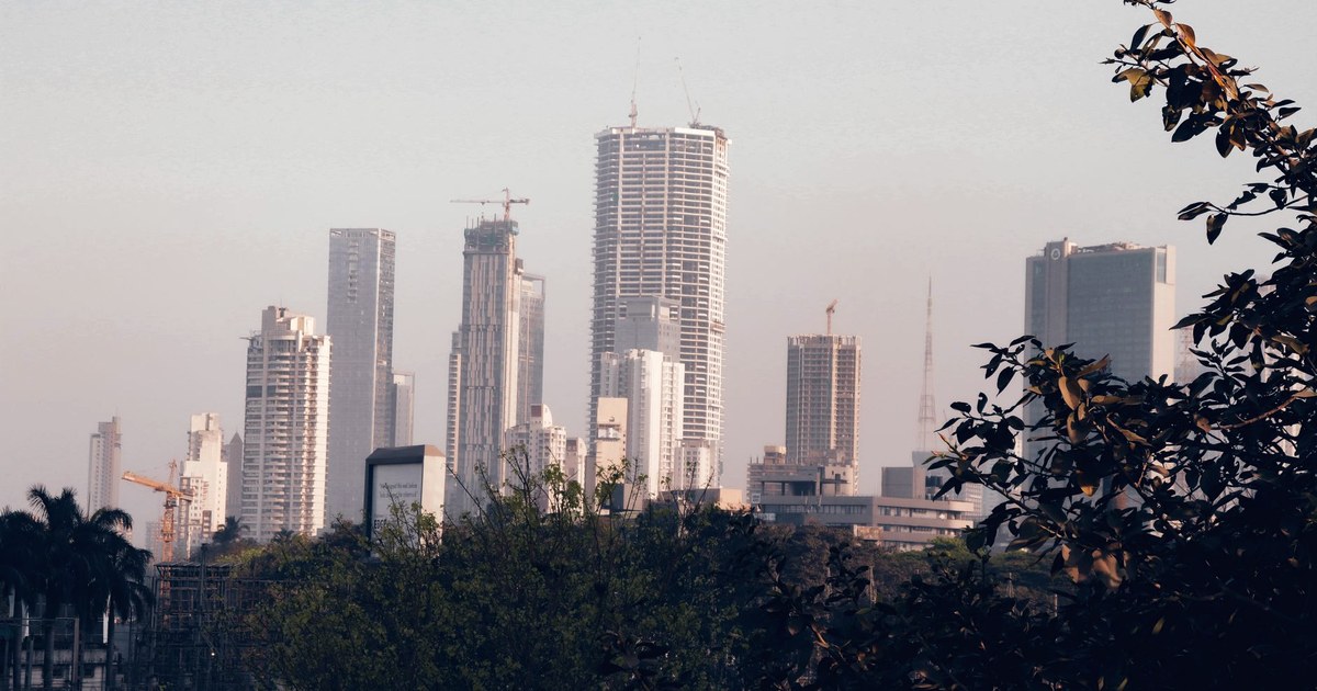 Residential and commercial towers under construction rise above trees in Mumbai in soft morning haze