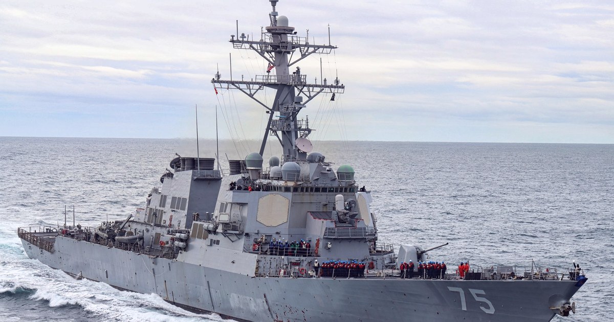 A US Navy Arleigh Burke class guided-missile destroyer underway at sea, crew assembled on deck