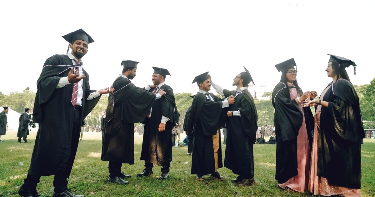 Indian university graduates in caps and gowns celebrating together outdoors after a convocation ceremony